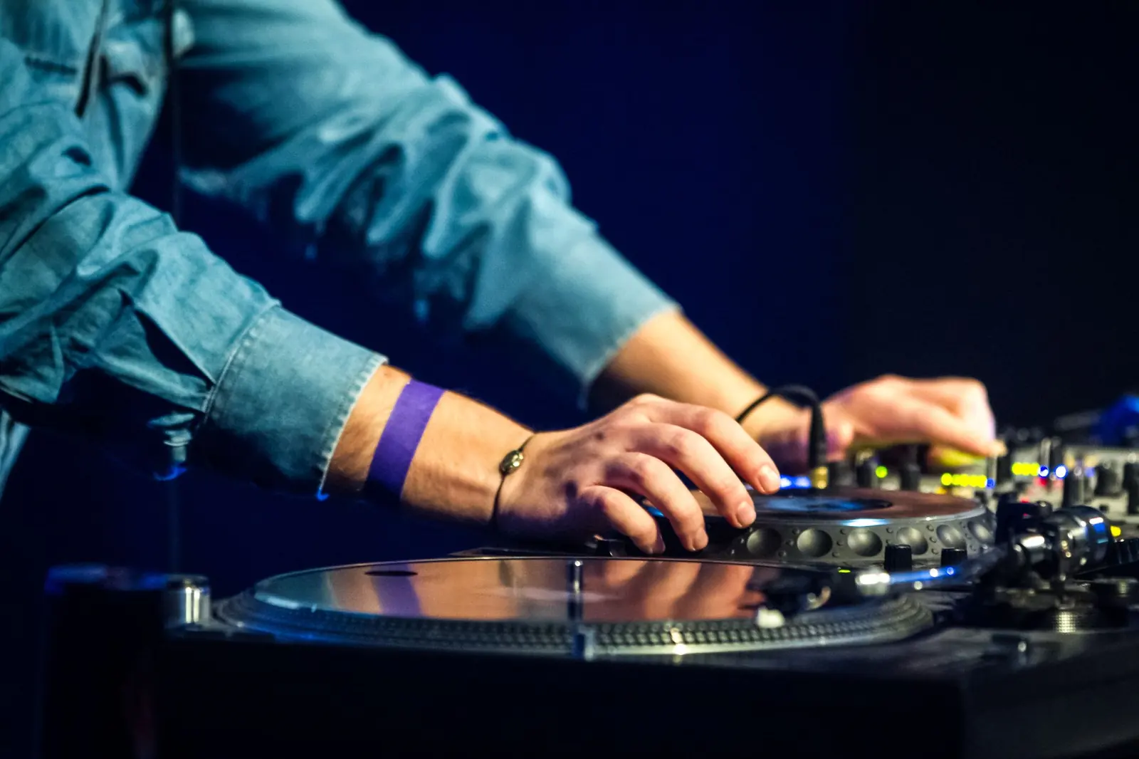 DJ mixing music on professional decks under blue event lighting